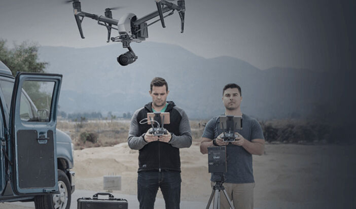 Two men fly the Inspire 2 Professional Film drone near a truck