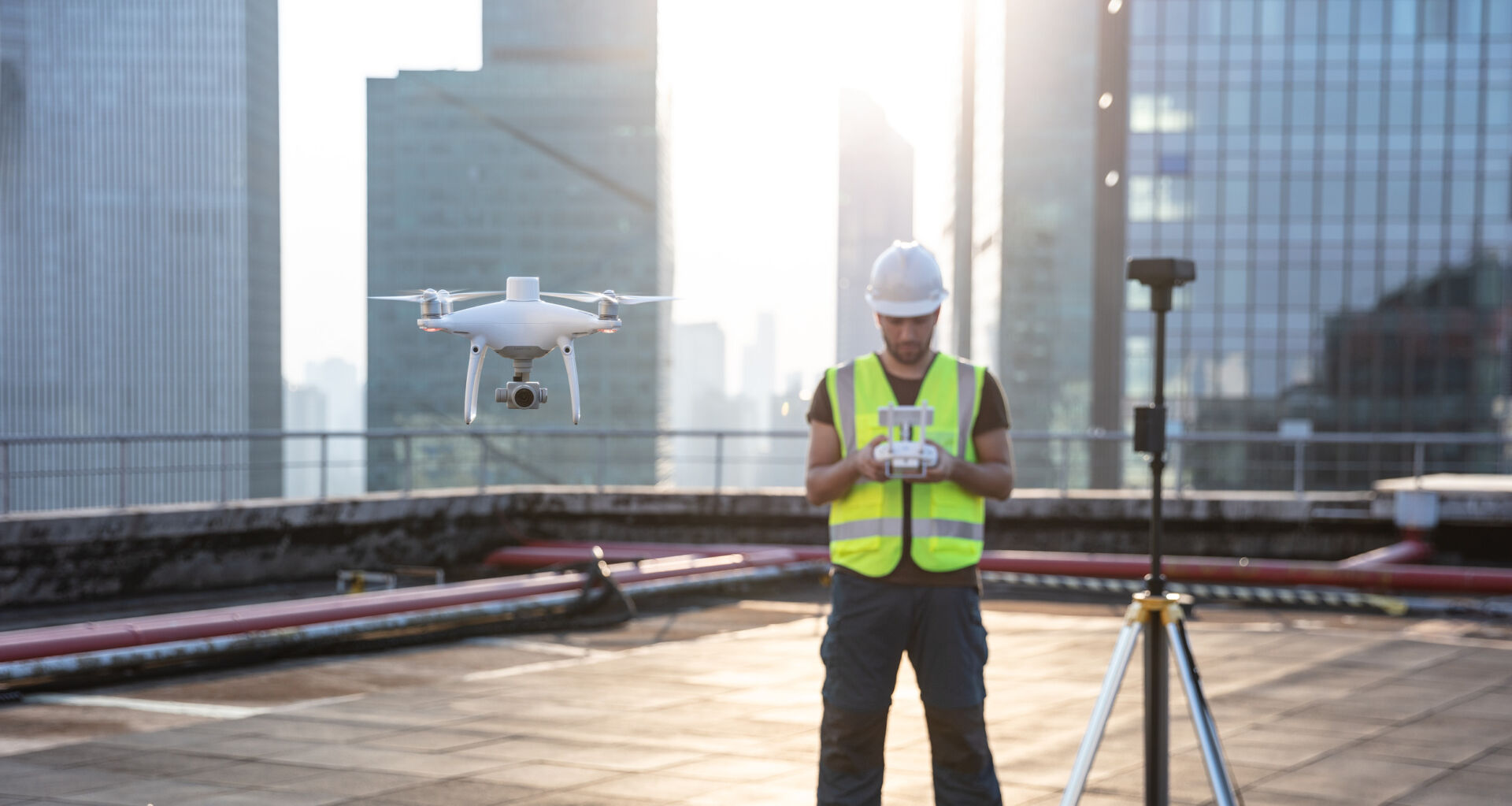 Worker using P4 RTK drone on rooftop during a surveying job or project in big city